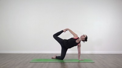 Yoga teacher performing yoga posture on green yoga mat on white background